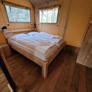 ein großes Bett in einem Zimmer mit zwei Fenstern in der Unterkunft Heated & brand new Forestlodge in Renesse