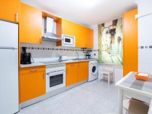 cocina con armarios de color naranja y lavadora en Apartamento "EL PEDROSO" en Tordesillas