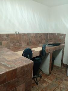 ein Badezimmer mit einem Waschbecken und einem schwarzen Stuhl in der Unterkunft Estudio Comodo y Tranquilo in Mexicali
