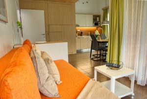a living room with an orange couch and a kitchen at Apartma Pikabooth Terme Topolšica in Topolšica