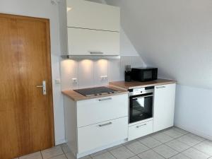 a kitchen with white cabinets and a stove top oven at Moderne Ferienwohnung in ruhiger Lage in Neetze