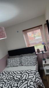a bedroom with a black and white bed and a window at Glamshouse in Bushbury
