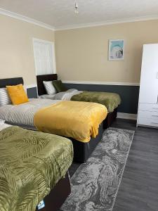 a room with three beds and a rug at Modern 4 Bed House for 9 guests in Tilbury
