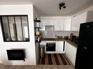 cocina con armarios blancos y nevera negra en Grand F2 dernier etage belle vue, en Le Blanc-Mesnil