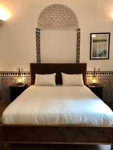 a bedroom with a large white bed with two night stands at Riad Dar Souika in Rabat