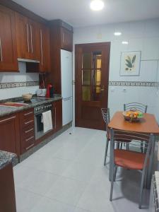 a kitchen with wooden cabinets and a table with a bowl of fruit on it at AGARIMO APARTAMENTO in Pontevedra
