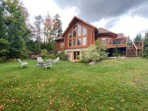 uma grande casa de madeira com cadeiras no quintal em Fiddler Lake Resort Chalet Deer 59 em Mille-Isles