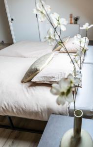 a bed with pillows and a vase with flowers on a table at Luxe Retreatsecret Of Ledeacker 