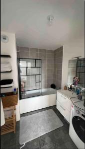 a bathroom with a bath tub and a sink at Grand F2 dernier etage belle vue in Le Blanc-Mesnil