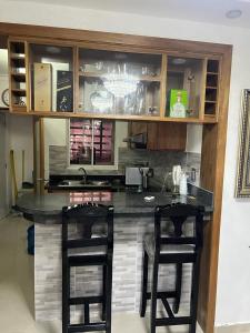 a kitchen with a counter with two bar stools at Residencial altos de la independencia in San Pedro de Macorís