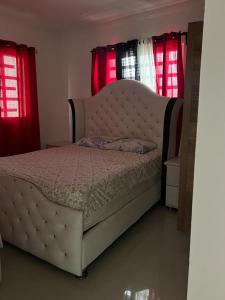 1 dormitorio con 1 cama grande y cortinas rojas en Residencial altos de la independencia, en San Pedro de Macorís