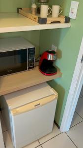 a microwave sitting on a shelf in a kitchen at Gran Lençóis Flat Barreirinhas in Barreirinhas
