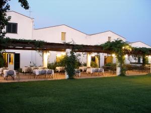 uma área de refeições exterior de um edifício branco com mesas e cadeiras em Relais Masseria Cardillo em Metaponto