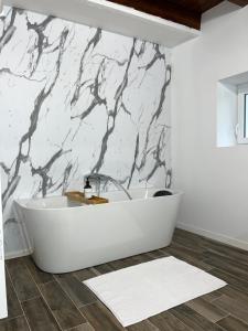 baño con bañera blanca y pared de mármol en Gîte Le Perche Rose, en Eymet