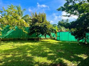 a garden with a green fence and trees at La Perla de Cobano in Puntarenas