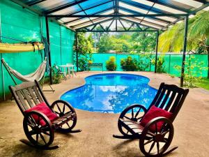 two rocking chairs sitting next to a swimming pool at La Perla de Cobano in Puntarenas