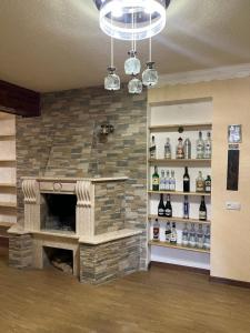 Fireside Fiesta Haven في كوتايسي: غرفة بها موقد حجري ورفوف مع زجاجات