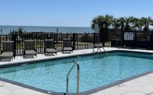 a swimming pool with chairs and the ocean in the background at Blue Palmetto Vacation Rentals in Myrtle Beach