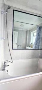 a bathroom with a mirror and a bath tub at StayViva - Spacoius 3 BR House - Garden, Games Room, Parking near Town Centre and Train station in Bracknell