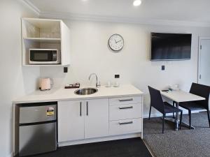 a kitchen with a sink and a microwave and a table at Superior Dunedin Apartments in Dunedin +12 photos