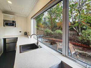 uma cozinha com um lavatório e uma grande janela em Superior Dunedin Apartments em Dunedin