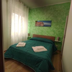 een slaapkamer met een groen bed en handdoeken bij Onda marina 1 in La Spezia