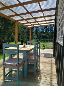 een patio met een houten tafel en stoelen onder een pergola bij BlackHouse in Federación