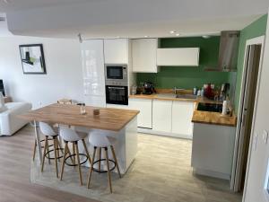 a kitchen with white cabinets and a wooden island with bar stools at A 15km du Mont-Saint Michel in Saint-James