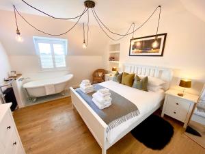 1 dormitorio con cama blanca y bañera en Kinnoull House near Stornoway Hot Tub/Pet Friendly, en Garrabost