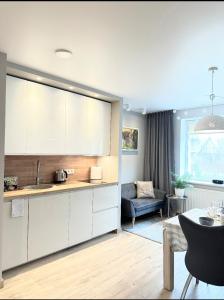 a kitchen with white cabinets and a living room at Miegu - Apartments in Druskininkai