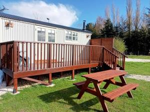 a wooden deck with a bench in front of a house at Woodpecker Shepherds Hut in Boston