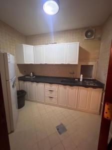 a kitchen with white cabinets and a light on the ceiling at ALHNOFF MAKKAH 1 in Aţ Ţunḑubāwī