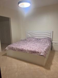 a bedroom with a bed with a purple comforter at ALHNOFF MAKKAH 1 in Aţ Ţunḑubāwī