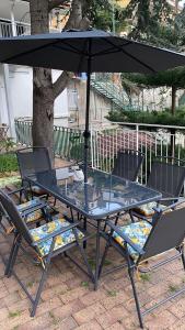 a glass table and chairs under an umbrella at La Perla del Mare Apartment Vietri sul Mare in Albori
