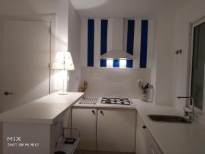 a white kitchen with a stove and a lamp at 1 linea playa Islantilla in Islantilla +15 photos