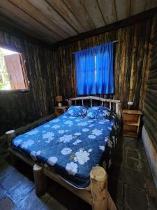 a bedroom with a bed with a blue comforter at Residencial El Cielo Cabaña Popeye y Cabaña Pipil in Los Naranjos