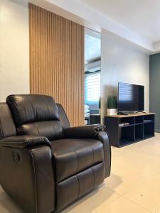 uma cadeira reclinável de couro numa sala de estar com televisão em CRIB 217 SUBIC BAY - Modern Fresh Condo em Olongapo