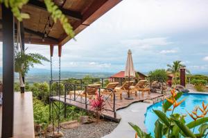 a villa with a pool and a patio with chairs and a umbrella at Buen Camino Hotel, San Mateo in San Mateo