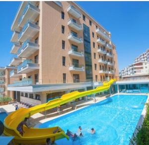 a pool with a slide in front of a building at Sunset Apartment in Vlorë