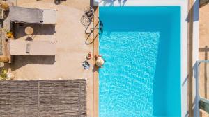 una vista sulla piscina con un uomo seduto accanto di Ocean Blue Villa by LLB - Beach in 6min walking a Mykonos Città