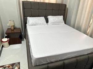 Una cama con sábanas blancas y almohadas. en Rejao Homes en Dar es Salaam