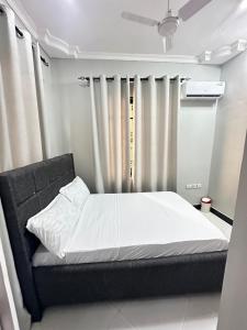 a bedroom with a bed with white sheets and curtains at Rejao Homes in Dar es Salaam