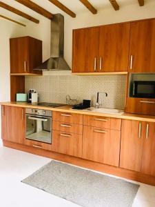 a kitchen with wooden cabinets and a stove top oven at Maison tout confort avec jardin et parking gratuit à Enghien Les Bains in Enghien-les-Bains