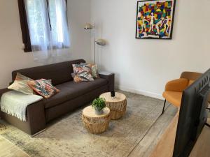 ein Wohnzimmer mit einem Sofa und 2 Tischen in der Unterkunft Maison situé au centre d'Enghien les Bains avec jardin et parking privé in Enghien-les-Bains