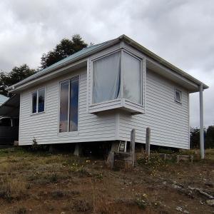 a small white house sitting on top of a field at Cabaña Carpintero negro in Dalcahue