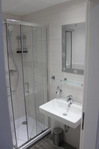 a white bathroom with a sink and a shower at Ferienhaus Kunz in Fehmarn