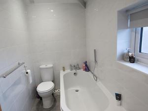 a white bathroom with a toilet and a bath tub at Hillside in Llanelli