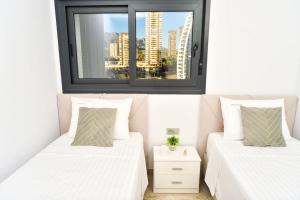 two beds in a room with a window at Benidorm Sunset Cliffs in Benidorm +44 photos
