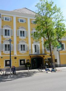 ein gelbes Gebäude mit einem Baum davor in der Unterkunft Hotel Gösser Bräu in Wels