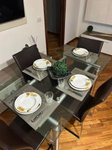 une table en verre avec quatre chaises et des assiettes dans l'établissement LA CASA DI AMBRA, à Limbiate